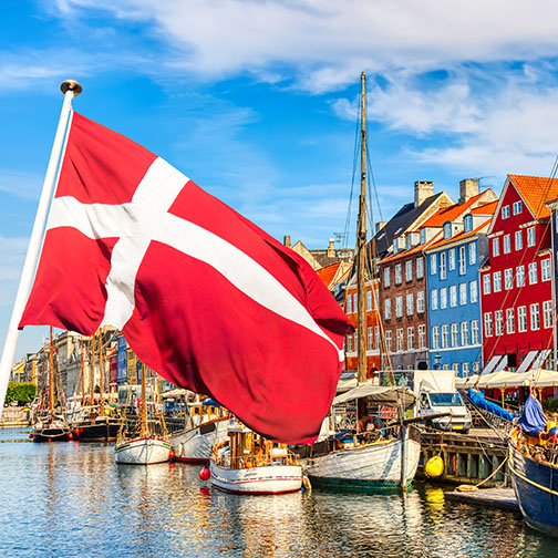 Scene in Copenhagen: Danish flag and colorful houses and boats on canal