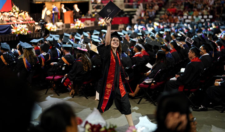 Craig Business School graduate raises her diploma in triump during Commencement